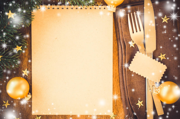 Weihnachtstisch mit braunem Notizbuch zum Schreiben von Rezept oder Menü auf Holztisch. Vintage oder rustikaler Stil. festlich gedeckter Tisch für Weihnachts- oder Neujahrsessen. - Foto, Bild