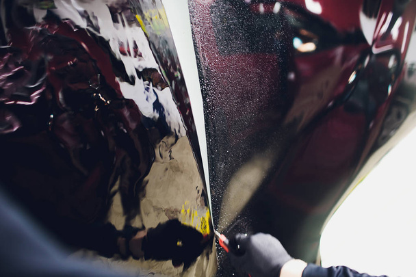 Applying tinting foil on car window in garage - Foto, afbeelding