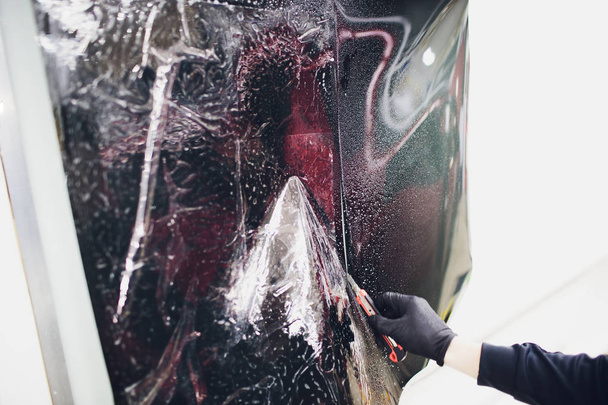 Applying tinting foil on car window in garage - Foto, Bild