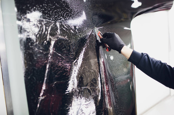 Applying tinting foil on car window in garage - Фото, изображение