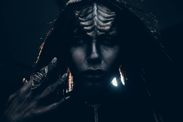 Portrait of young woman in image of humanoid and extraterrestrial alien with horns on her head, finger ring on her hand and demonic eyes. - Photo, Image