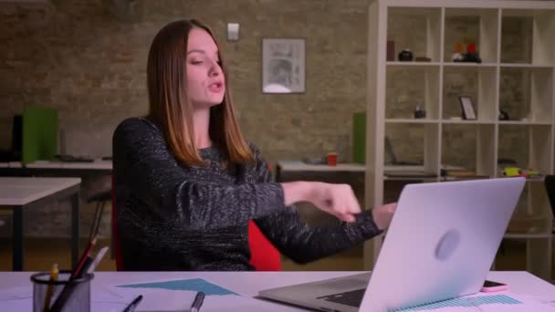 Young ginger woman actively dancing on working place and feeling happy in office. - Materiał filmowy, wideo