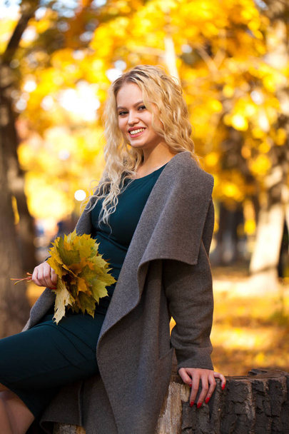 Portrait of a young beautiful blonde woman in gray coat on a background of autumn street - Foto, Imagem