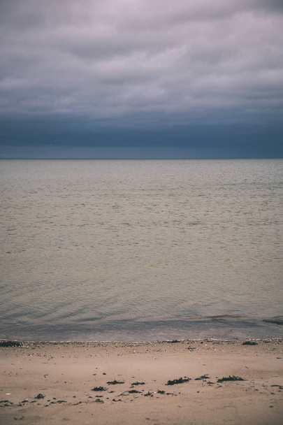 скалистое побережье Латвии с текущей водой в море и большими скалами в конце осени. Скучные цвета - винтажный ретро-вид
 - Фото, изображение