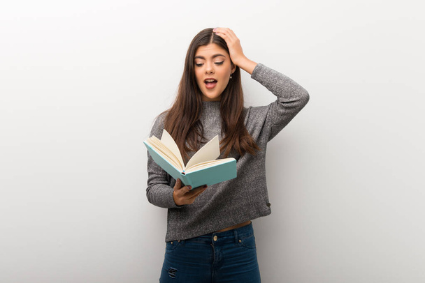 Έφηβο κορίτσι σε απομονωμένες έκπληκτος απολαμβάνοντας διαβάζοντας ένα βιβλίο λευκό backgorund - Φωτογραφία, εικόνα
