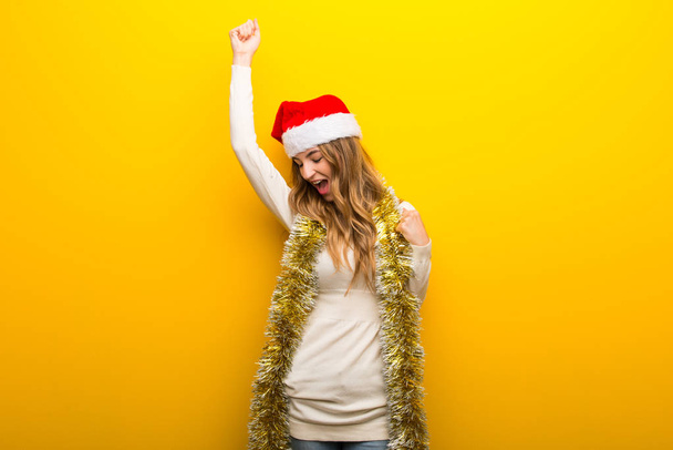 勝利を祝う黄色背景にクリスマス休暇を祝う女の子 - 写真・画像
