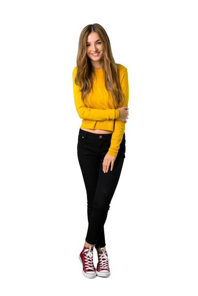 A teljes hosszúságú lövés egy fiatal lány boldog kifejezés elszigetelt fehér háttér sárga pulóver - Fotó, kép