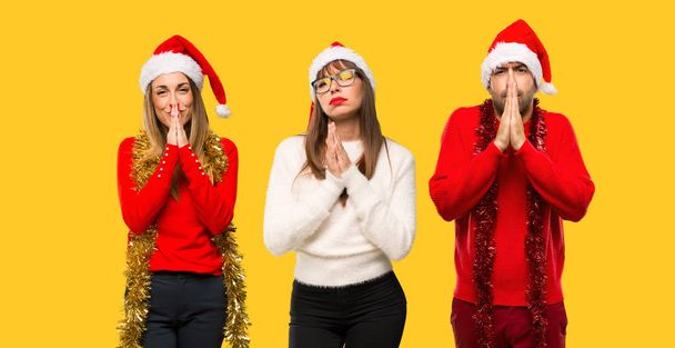 Un grupo de personas Mujer rubia vestida para las vacaciones de Navidad mantiene la palma junto. Persona pide algo sobre fondo amarillo
 - Foto, Imagen
