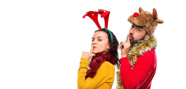 Couple habillé pour les vacances de Noël montrant un signe de fermeture de la bouche et geste de silence sur fond isolé
 - Photo, image