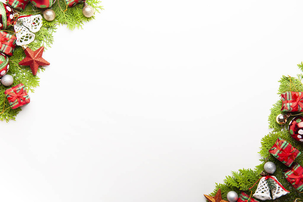 Bovenaanzicht van Kerstmis achtergrond, sjabloon met versieringen van ballen, geschenkverpakkingen, witte klokken op fir tree op witte achtergrond met kopie ruimte, ornamenten voor Nieuwjaars groeten. - Foto, afbeelding
