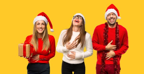 Група людей білявка одягнені для різдвяних свят, посміхаючись багато під час покласти руки на грудях на жовтому фоні - Фото, зображення