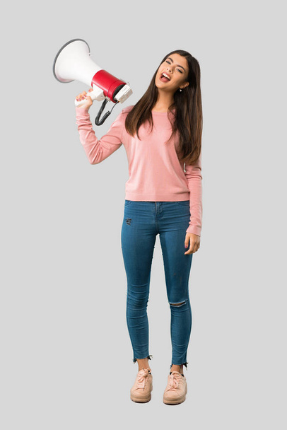 Full body of Teenager girl with pink shirt holding a megaphone on isolated grey background - Valokuva, kuva