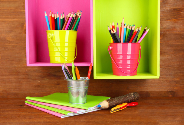 Colorful pencils in pails on shelves on wooden background - Фото, изображение