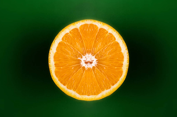 Fresh orange cut in half against dark green background - Фото, зображення
