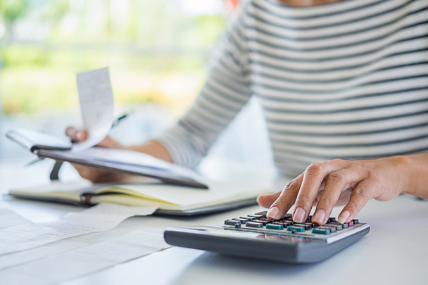 Woman with bills and calculator. Woman using calculator to calculate bills at the table in office. Calculation of costs. - Foto, Imagem