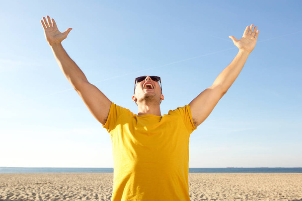 Ritratto di felice uomo spensierato tifo con le braccia alzate in spiaggia
 - Foto, immagini