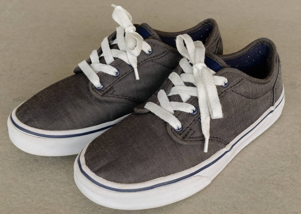 ビンテージ スタイルの白灰色の背景にスポーツ グレー スニーカー靴を閉じる - 写真・画像
