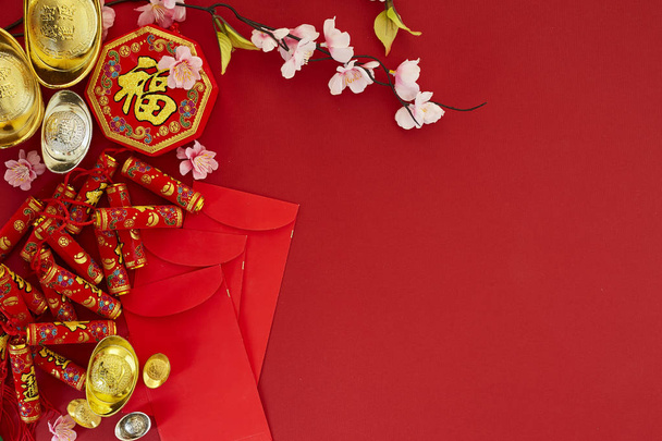 Chinese new year 2019 festival decorations.firecrackers,gold ingot,red packet,plum blossom,on red background. Top view accessories. Translation: Fu meaning good fortune, Chun meaning spring. - Photo, image