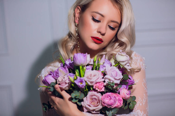 Pretty young girl. Blonde woman with luxurious long curly hair. Brides morning. Taking wedding bouquet in hands - Zdjęcie, obraz