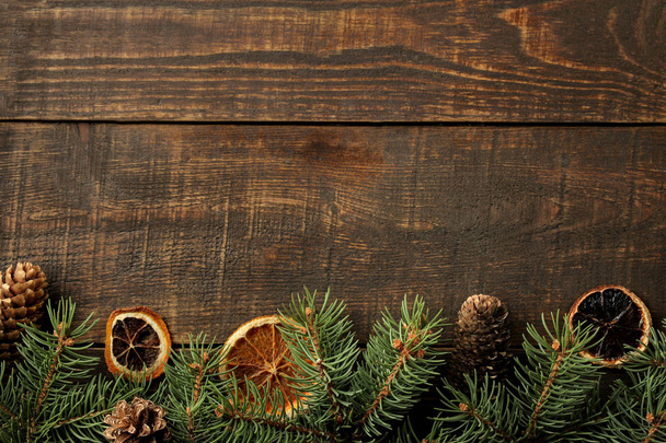 Marco de Navidad y Año Nuevo para texto con conos de pino y árbol de Navidad y naranjas secas sobre fondo marrón. vista desde arriba
. - Foto, Imagen