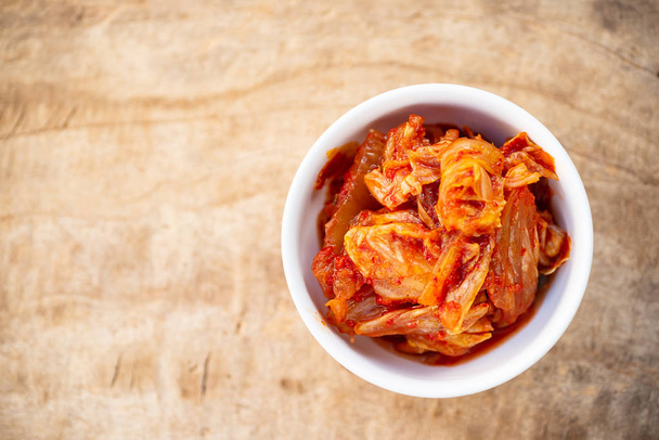 Капуста кимчи в миске на деревянном столе, корейская еда - Фото, изображение