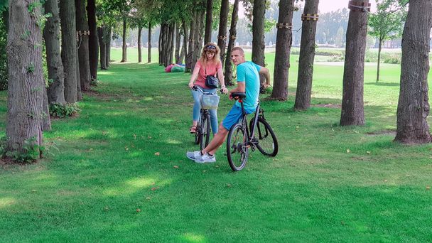 Mann und Frau Fahrrad fahren auf einer Wiese zwischen Bäumen, gesunder Lebensstil - Foto, Bild