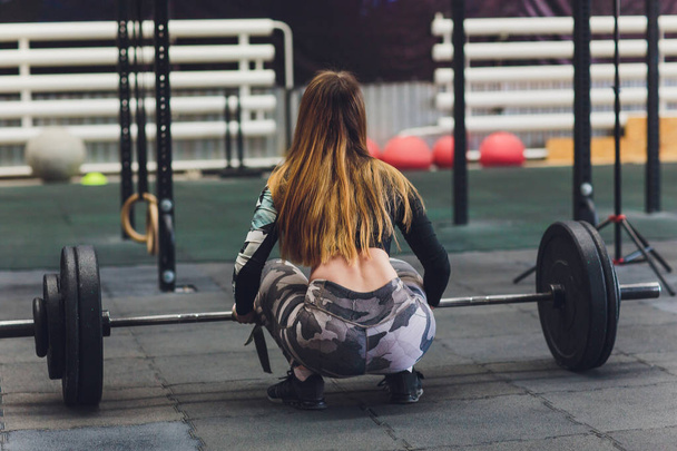 Attractive young sports woman with barbell. Deadlift. rear view, athletic womans ass - Valokuva, kuva