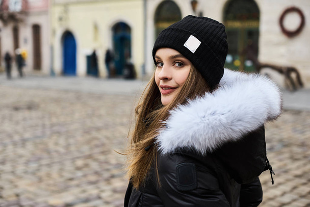 Portrait of a young fashionable girl walking on the street of the city in winter time - Foto, Bild