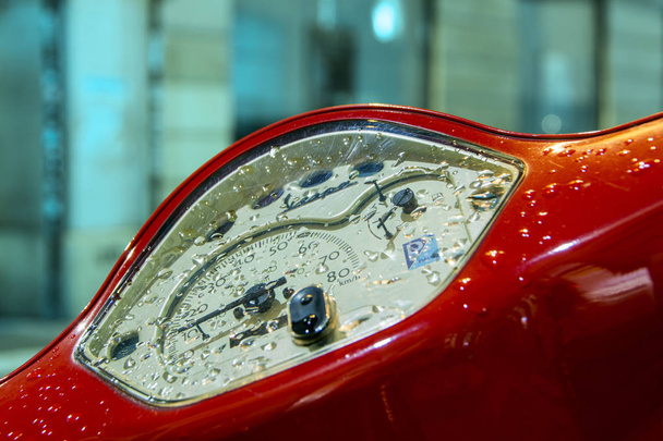 Paris, France - November 10, 2018: Close-up of the red vintage Vespa scooter speedometer covered with the rain drops with night city on blurred background - Photo, Image