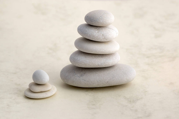 Harmonie und Gleichgewicht, Cairn, Gleichgewichtssteine auf hellem Hintergrund, Felsen-Zen-Skulptur, Gruppe weißer Kieselsteine, Türmchen, klein, Kind, schwarzer Stein - Foto, Bild