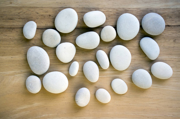 Group of zen stones on wooden mat, pebbles, light grey, dark grey, white, massage pebbles - Foto, Imagen