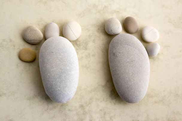 Two tiny stone feet and eight toes on wooden background, stone in the shape of a human feet - Photo, Image