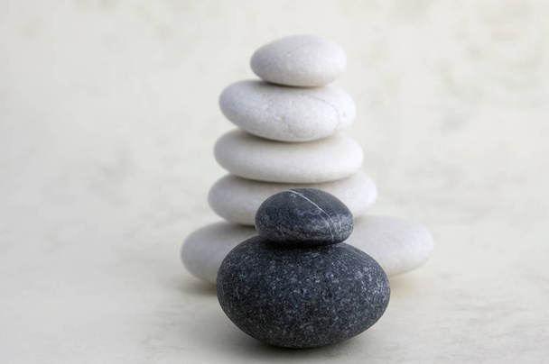Harmony and balance, cairn, poise stones on light background, rock zen sculpture, group of white pebbles, group of towers, small, child, black stone - Zdjęcie, obraz