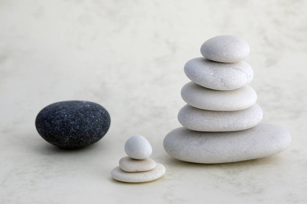 Harmony and balance, cairn, poise stones on light background, rock zen sculpture, group of white pebbles, group of towers, small, child, black stone - Фото, зображення