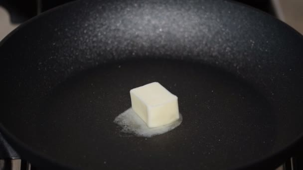 Trozo de mantequilla derretida en una sartén antiadherente
. - Imágenes, Vídeo