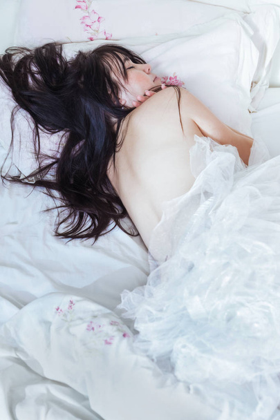 A beautiful brunette sleeping on a bed at morning. Happy woman with a romantic dreams. - Zdjęcie, obraz