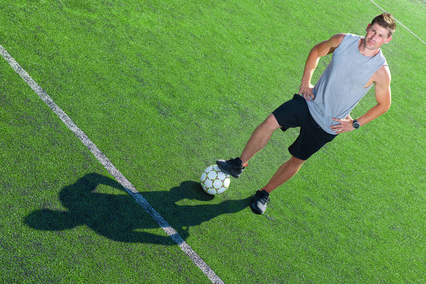 Jugador de fútbol de pie en un campo verde sonriendo sosteniendo su pelota
 - Foto, Imagen