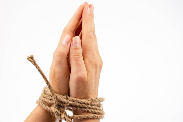 Female hands are folded palms inward and tied with a rope on a white background - 写真・画像