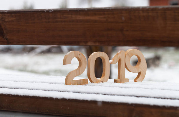 Wooden figures 2019 on the snowy bench. New year and christmas theme. - Photo, image