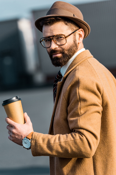 guapo hombre de negocios en sombrero y vasos sosteniendo café para llevar
 - Foto, imagen