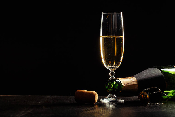 bottle of champagne and glass over dark background - Foto, afbeelding