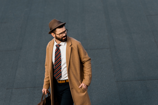 Erwachsener Geschäftsmann mit Brille und Hut, die Hand in der Tasche - Foto, Bild