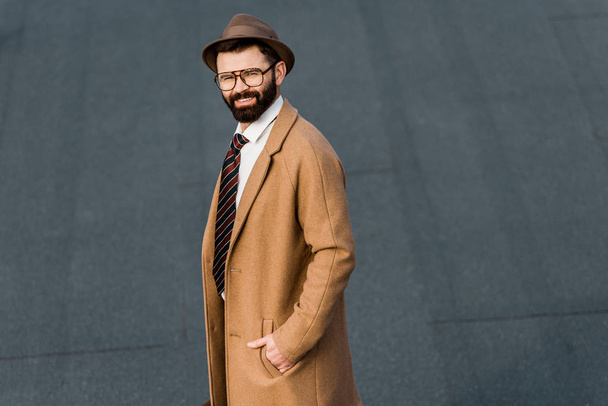 smiling bearded businessman in glasses posing with hand in pocket - 写真・画像