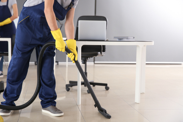 Janitor hoovering floor in office - Photo, Image