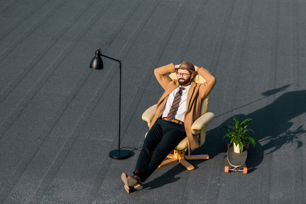 Erwachsener Geschäftsmann im Mantel ruht tagsüber im Sessel  - Foto, Bild