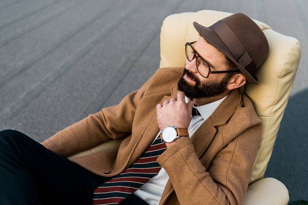 promyšlené vousatý podnikatel v brýlích sedí v křesle - Fotografie, Obrázek
