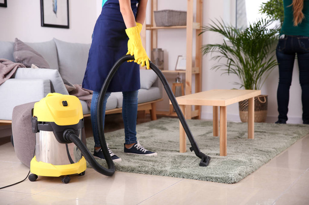 Female janitor hoovering carpet in flat - Zdjęcie, obraz