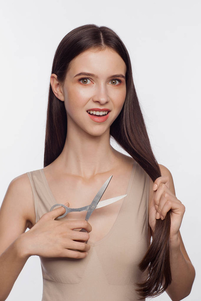 Beautiful young woman cuts off her hair by scissors - Fotó, kép