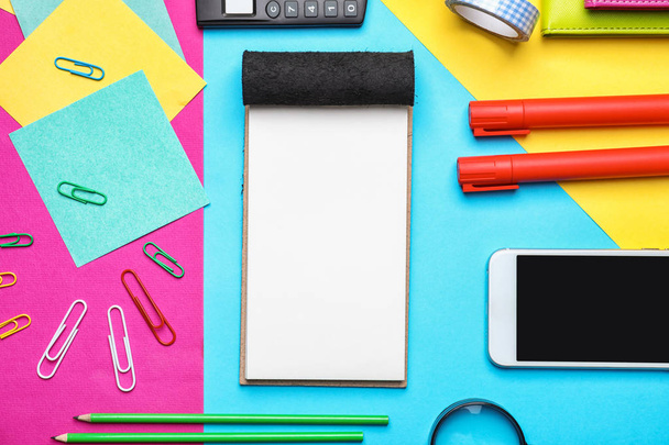 Mobile phone and school stationery on color background, top view - Photo, image