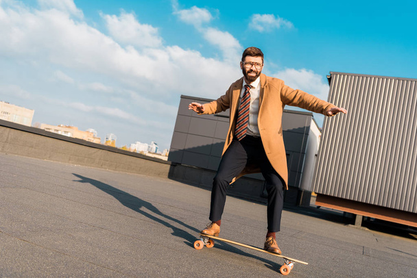 bearded businessman in coat riding on penny board  - Photo, Image